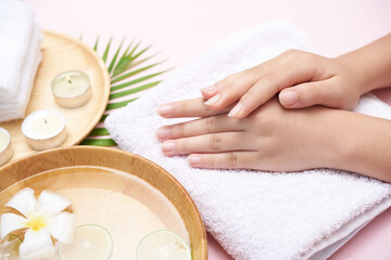 Woman soaking her hands in bowl of water and flowers, Spa treatment and product for female feet and hand spa, massage pebble, perfumed flowers water and candles, Relaxation. Flat lay. top view.