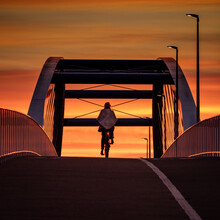 Rowerzystka Jedzie Przez Most Na Tle Czerwonego Nieba