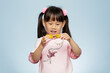 © M-image - young girl holding traditional  Chinese moon cake against plain blue background