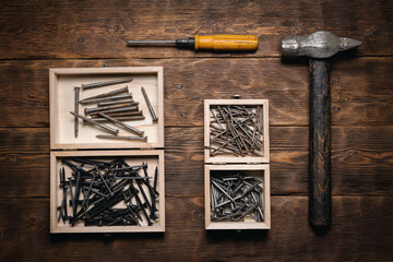 Wall Mural - Old hammer, screwdriver, nails and screws in the boxes on the wooden flat lay workbench background.