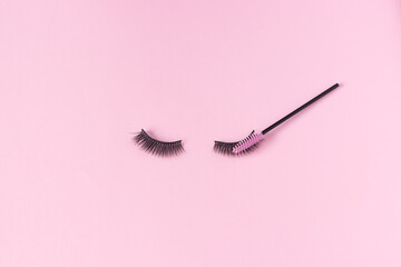 Wall Mural - Artificial eyelashes on a pink background and an eyelash brush. The concept of eyelash extensions, makeup.