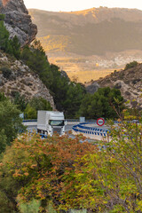 Wall Mural - Truck with refrigerated semi-trailer driving on a highway between mountains and lined with trees in autumn.