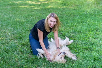 Wall Mural -  woman playing with her retriever on green grass