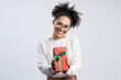 © speed300 - Take it. Young happy woman wearing white knitted sweater giving gift box to camera with excited smile, greeting on holiday and sharing present. Indoor studio shirt isolated on white background