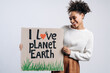 © speed300 - I love planet Earth. Multiracial cheerful woman holding carton placard with signs and looking at it. Concept of nature destruction and eco activism