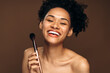 © speed300 - Waist up photo of a young woman looking relaxed and smiling while holding brush for makeup. Beauty procedures concept