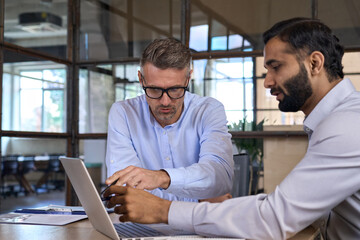 Wall Mural - Diverse business people businessmen negotiating at boardroom meeting using working on laptop pc computer. Multiethnic executive team discussing financial partnership sitting at table in office.