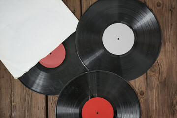 Three old vinyl records in paper case on wooden rustic background.