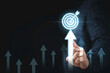 © Dilok - Hand touching up arrow with virtual target board for enhance and set up business objective target  goal concept.