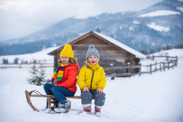 Wall Mural - Kids boy and little girl enjoying a sleigh ride. Children sibling together sledding, play outdoors in snow on mountains in winter.