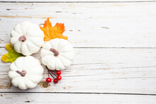 Autumn Side Border Of White Pumpkins And Autumn Leaves Over A Rustic White Wood Background, Top View