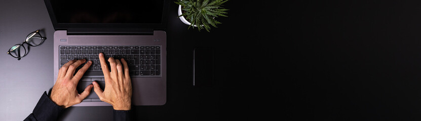 Person using a laptop computer on a solid color background