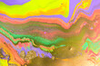 Streams of liquid purple, pink, green and gold ink curls. Waves of fluid vivid golden fluid paint.