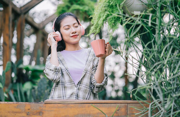 Wall Mural - Young Asian woman drinking tea in the garden