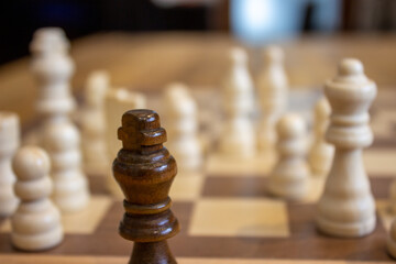 Poster - Selective shot of a black king chess piece in front of the white pieces on a chessboard