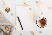 White Sheet Of Notebook With Pen On White Table With Cup Of Cocoa Or Coffee, Candle And Festive Garland. Concept Planning, Wish List For The New Year. Mockup For Lettering, Art Drawing.
