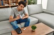 © Krakenimages.com - Young hispanic diabetic man measuring glucose sitting on the sofa at home.