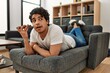 © Krakenimages.com - Young hispanic man talking on the smartphone lying on the sofa at home.