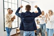 © Krakenimages.com - Group of young business workers smiling and clapping. Young businessman doing strong gesture with arms on back view at the office.