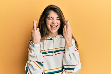 Poster - Young caucasian woman wearing casual clothes gesturing finger crossed smiling with hope and eyes closed. luck and superstitious concept.