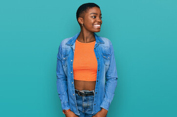 Sticker - Young african american woman wearing casual clothes looking away to side with smile on face, natural expression. laughing confident.