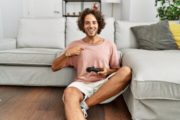 Sticker - Young hispanic man playing video game holding controller at home pointing finger to one self smiling happy and proud