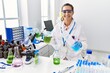 © Krakenimages.com - Young hispanic woman working at scientist laboratory smiling with a happy and cool smile on face. showing teeth.