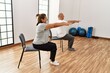 © Krakenimages.com - Middle age hispanic couple stretching using chair at sport center.