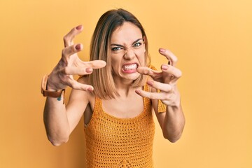 Wall Mural - Young caucasian blonde woman wearing casual yellow t shirt shouting frustrated with rage, hands trying to strangle, yelling mad