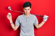 © Krakenimages.com - Young hispanic man holding golf ball skeptic and nervous, frowning upset because of problem. negative person.