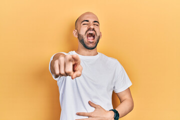 Sticker - Young bald man wearing casual white t shirt laughing at you, pointing finger to the camera with hand over body, shame expression