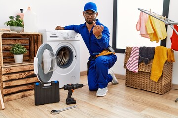 Wall Mural - Young indian technician working on washing machine showing middle finger, impolite and rude fuck off expression