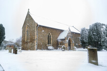 All Saints Church In The Small Village Of Sutton In The British Countryside, It Is Totally Covered In Deep Snow During A Rare Snow Storm In The UK