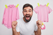 © WHstudio Leushin N - Photo of bearded young man yells with loud voice keeps mouth widely opened clenchesfists reacts on something awesome wears casual t shirt poses against white background with pink items of clothes