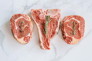 Wall Mural - three delicious steaks ready to grill on a white marble surface