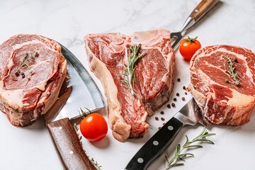 Wall Mural - three delicious steaks ready to grill on a white marble surface