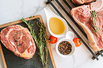 Wall Mural - three delicious steaks ready to grill on a white marble surface