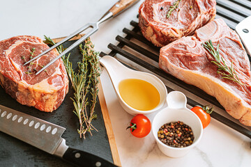 Wall Mural - three delicious steaks ready to grill on a white marble surface