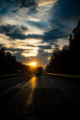 Poster - Vertical shot of cars driving on the road on a sunset background