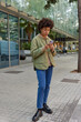 © wayhome.studio  - Outdoor shot of serious woman dressed in stylish clothing uses cellular for making quick payment texts in social media chats watches videos online on gadget stands on city pavement near shopping mall