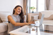 © Dragana Gordic - Communication is very important. Portrait of young smiling woman sitting on sofa at home with laptop. Pretty young woman using her laptop while sitting on the floor at home.