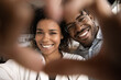 © fizkes - Close up sincere loving young married african american family couple showing heart symbol, looking at camera. Happy bonding millennial mixed race man woman demonstrating tender feelings or support.