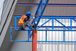 © Prapat - Low angle view of construction worker with safety equipment welding metal on roof structure of warehouse building in construction site