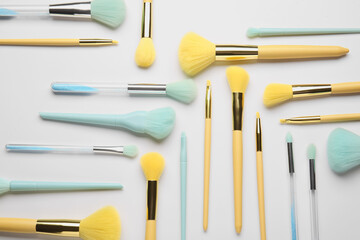 Different stylish makeup brushes on light background