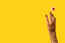 Hand Of Zombie With Human Eye On Stick Against Color Background