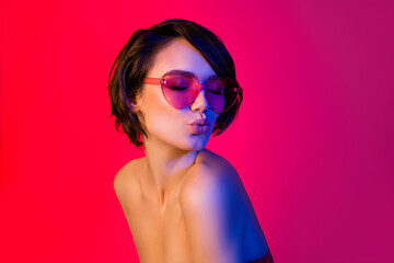 Portrait of attractive dreamy funky girl wearing specs sending air kiss isolated over bright red multicolor color background