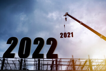 Silhouette of construction worker with crane and cloudy sky for preparation of welcome 2022