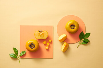 Sticker - Blank lable for advertising with persimmon . Whole persimmon and persimmon seeds, leaves on podium circle on color background. Top view flat lay.