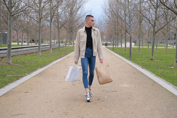 Wall Mural - Young man wearing make up walking with shopping bags and listening music.