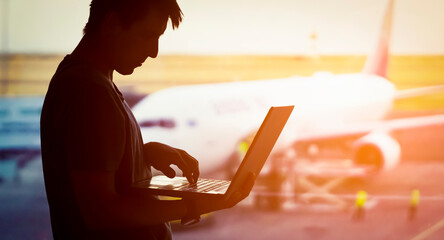 A young man is working on a laptop at the airport 